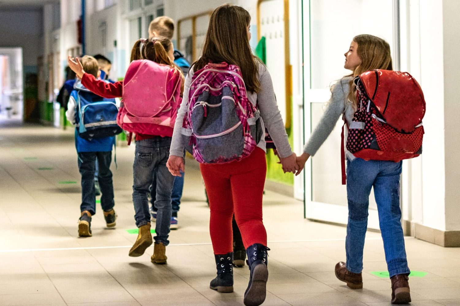 Back view group of schoolchildren going together in a classroom