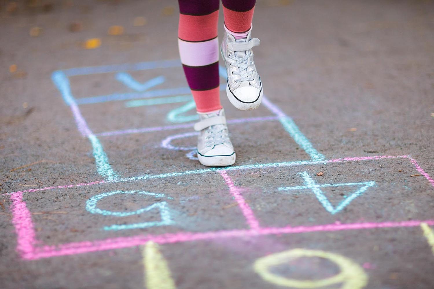 Close up of a little girl playing hopscotch outdoors